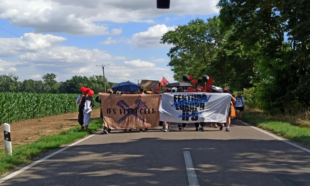 Das Bild zeigt einen Protestierende mit Transparenten auf einer Straße.